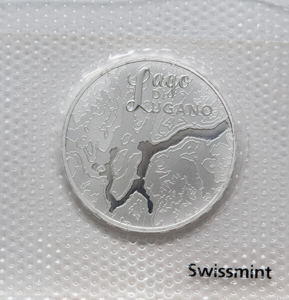 Münze Schweiz 20 Franken 2025 „Lago di Lugano“ Stempelglanz – Vorderseite zeigt den See in Vogelperspektive, Rückseite Symbol „Wasserturm Europas“.